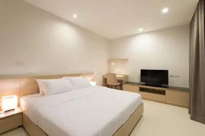 a bedroom with a white bed and a flat screen tv at The Silver Palm Wellness Resort in Bangkok