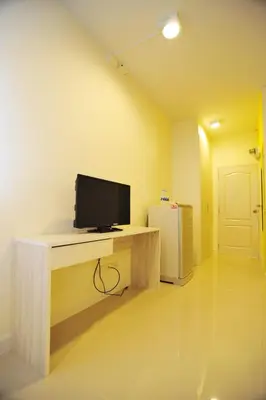 a room with a desk with a tv and a refrigerator at The Garden Living in Bangkok