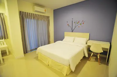 a bedroom with a white bed and a chair at The Garden Living in Bangkok