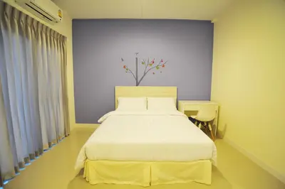 a bedroom with a white bed and a blue wall at The Garden Living in Bangkok