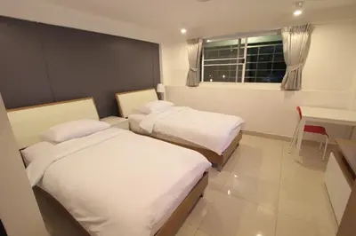 two beds in a room with a table and a window at Napaville Huai Khwang in Bangkok