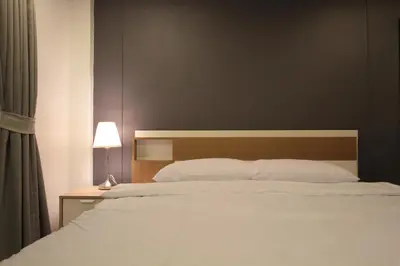 a bedroom with a large white bed with a wooden headboard at Napaville Huai Khwang in Bangkok