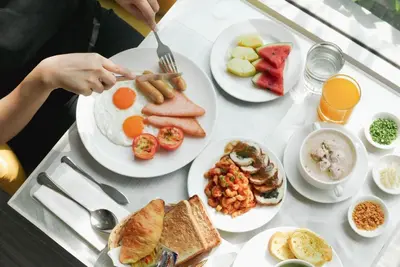 a table with plates of breakfast food on it at Le Tada Residence in Bangkok