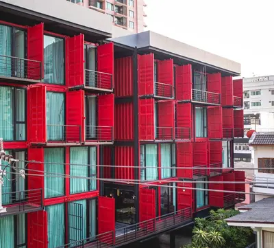 a red building with balconies on the side of it at Sleep Box Hotel Sukhumvit 22 in Bangkok