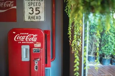 a red cocacola machine is next to a wall at Sleep Box Hotel Sukhumvit 22 in Bangkok
