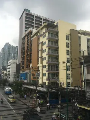 a tall building on a city street with cars at Diamond Bangkok Apartment in Bangkok