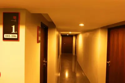 a hallway with a door and a sign on a wall at The Bangkok Major Suite in Bangkok