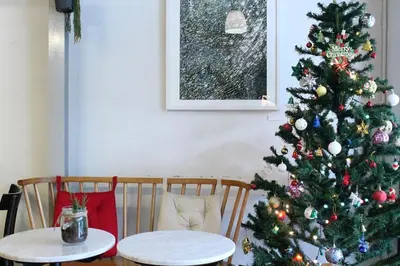 a christmas tree in a living room with two tables at Good One Poshtel & Cafe Bar in Bangkok