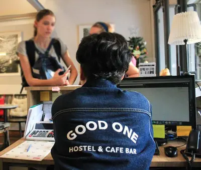 a woman sitting at a desk in front of a computer at Good One Poshtel & Cafe Bar in Bangkok