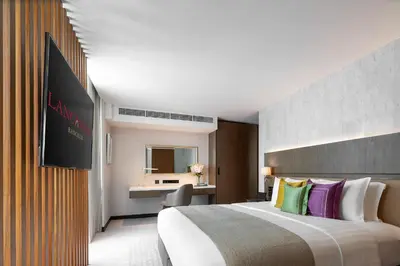 a hotel room with a large bed with colorful pillows at Lancaster Bangkok in Bangkok