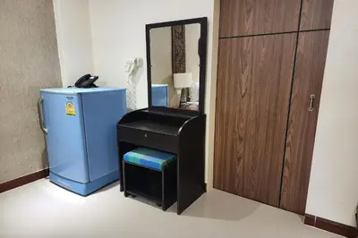 a bathroom with a small refrigerator next to a mirror at Kim Hotel At Bangplong in Bangkok
