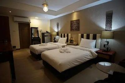 a hotel room with two beds with white sheets at Kim Hotel At Bangplong in Bangkok
