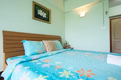 a bed with a blue bedspread with flowers on it at The Garden Place Bangkok in Nonthaburi