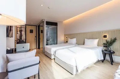 a hotel room with two beds and a couch at Mii Hotel Srinakarin in Bangna