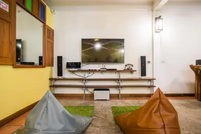 a room with a flat screen tv and a table with a table at Banthat Thong Hostel in Bangkok
