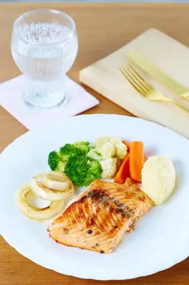 a white plate with fish and vegetables on a table at Uncle Loy's Boutique House in Bangkok