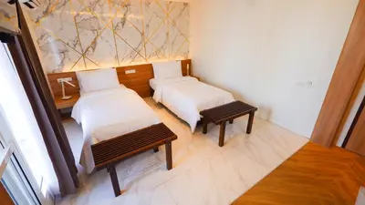 a room with two beds and a bench and a painting at Pinnacle Dream in Bangkok