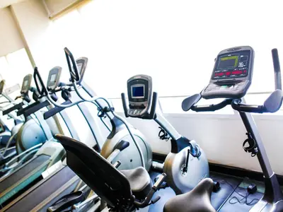 a row of exercise bikes in a gym with a cell phone at The Patra Hotel - Rama 9 in Bangkok
