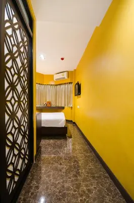 a bedroom with a bed and a yellow wall at Khaosan Palace Hotel in Bangkok