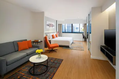 a living room with a couch and a bed at PARKROYAL Suites Bangkok in Bangkok