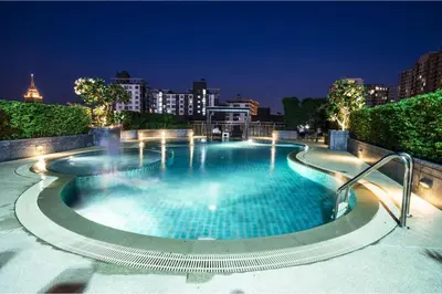 a large swimming pool in a city at night at Olive Hotel & Residence Bangkok Sukhumvit 101 near True Digital Park in Bangkok
