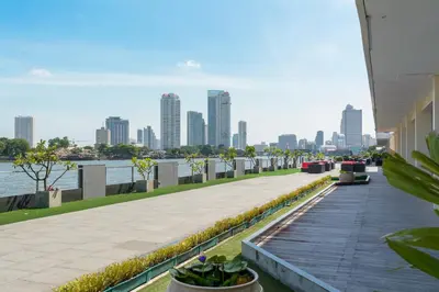 a walkway next to a river with a city skyline at Ramada Plaza by Wyndham Bangkok Menam Riverside in Bangkok