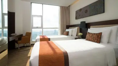 a hotel room with two beds and a desk at JC Kevin Sathorn Bangkok Hotel in Bangkok