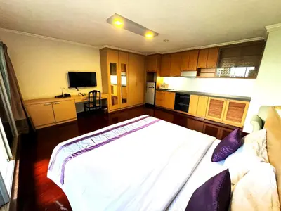 a bedroom with a white bed and a kitchen at Collection O The Step Sathorn in Bangkok