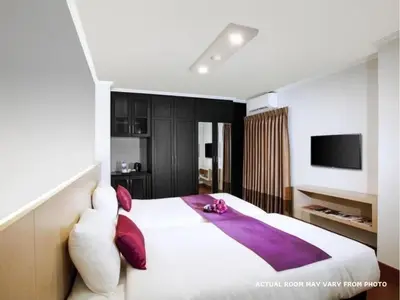 a bedroom with a large white bed with purple pillows at Collection O The Step Sathorn in Bangkok