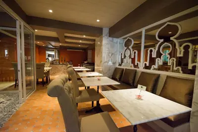 a restaurant with wooden tables and chairs and a wall with a mural at Violet Tower at Khaosan Palace in Bangkok