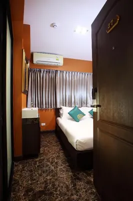 a small room with a bed and a window at Violet Tower at Khaosan Palace in Bangkok