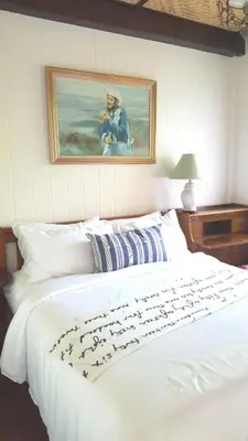 a bedroom with a white bed with a painting on the wall at Villa Mungkala in Bangkok