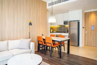 a kitchen and living room with a table and chairs at Marriott Executive Apartments Bangkok, Sukhumvit 101 in Bangkok