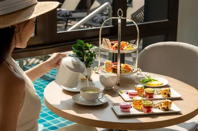 a woman sitting at a table with a tray of food at Marriott Executive Apartments Bangkok, Sukhumvit 101 in Bangkok