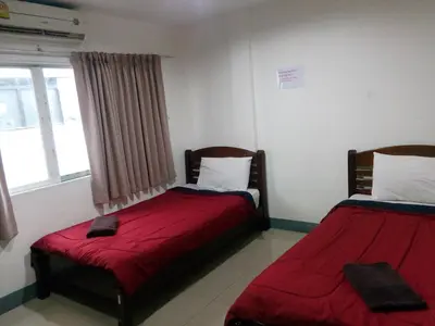 two beds in a room with red sheets and a window at Alsana Hotel in Bangkok