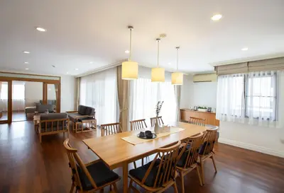 a dining room and living room with a wooden table and chairs at Baan Sawasdee Residence in Bangkok