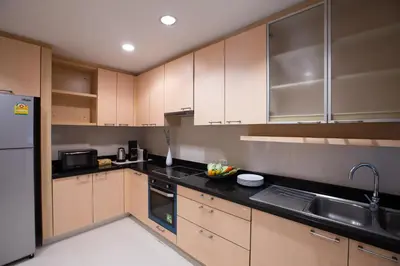 a kitchen with wooden cabinets and a black counter top at Baan Sawasdee Residence in Bangkok