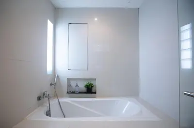 a white bath tub in a bathroom with a mirror at Baan Sawasdee Residence in Bangkok