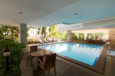 a swimming pool with a table and chairs next to it at Baan Sawasdee Residence in Bangkok
