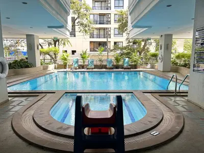 a pool at a hotel with a chair in the foreground at Baan Sawasdee Residence in Bangkok
