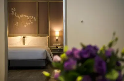 a bedroom with a bed with purple flowers in the foreground at imm hotel Ladprao Bangkapi Bangkok in Bangkok