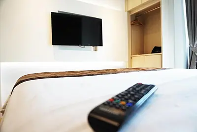 a remote control sitting on a bed with a tv at Aspira G Sukhumvit 33 in Bangkok