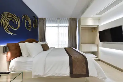 a bedroom with a large white bed and a television at Aspira G Sukhumvit 33 in Bangkok