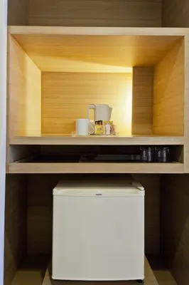 a kitchen with a shelf with a coffee maker on it at Trinity Silom Hotel in Bangkok