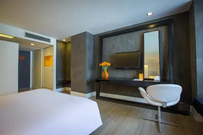 a bedroom with a bed and a tv and a chair at Trinity Silom Hotel in Bangkok
