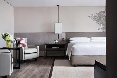 a bedroom with a bed and a chair at Bangkok Marriott Marquis Queens Park in Bangkok