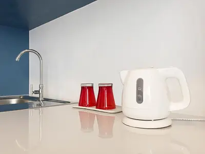 a white coffee maker and two red cups on a kitchen counter at 128 room and massage in Bangkok