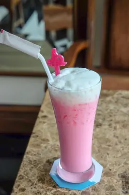 a pink drink sitting on a counter with a straw at Methavalai Residence Hotel in Bangkok