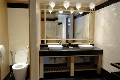 a bathroom with two sinks and a toilet and a mirror at Methavalai Residence Hotel in Bangkok