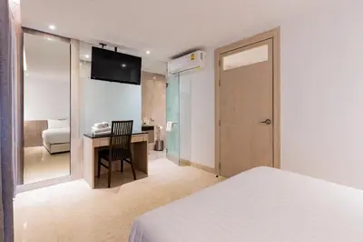 a bedroom with a bed and a desk with a television at Sukhothai Residence Ruam Ruedi in Bangkok